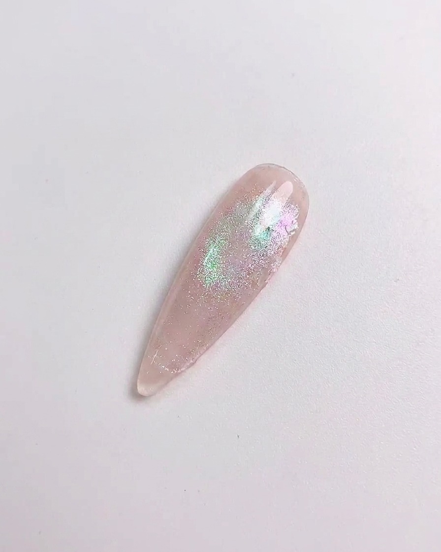 Una herramienta de silicona frotando polvo aurora sobre la superficie curada de la uña.