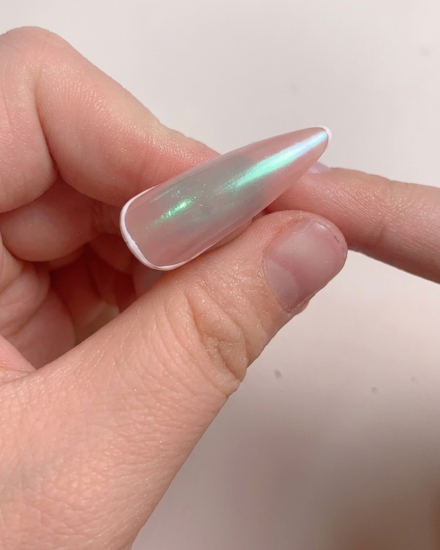 Un pincel aplicando una capa de gel reforzador sobre la uña esmaltada.