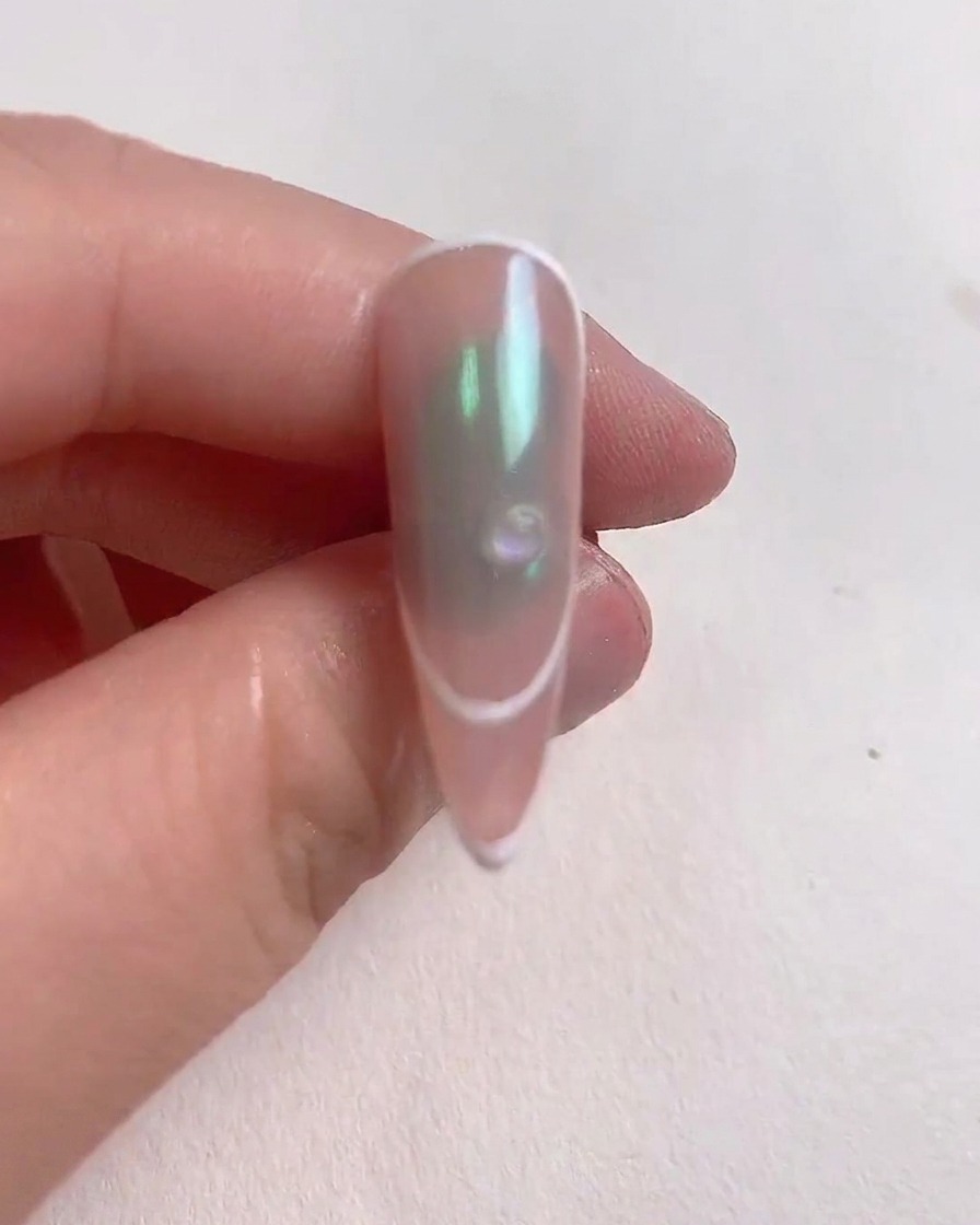 Una pequeña gota transparente de gel reforzador colocada en el centro de una uña decorada.
