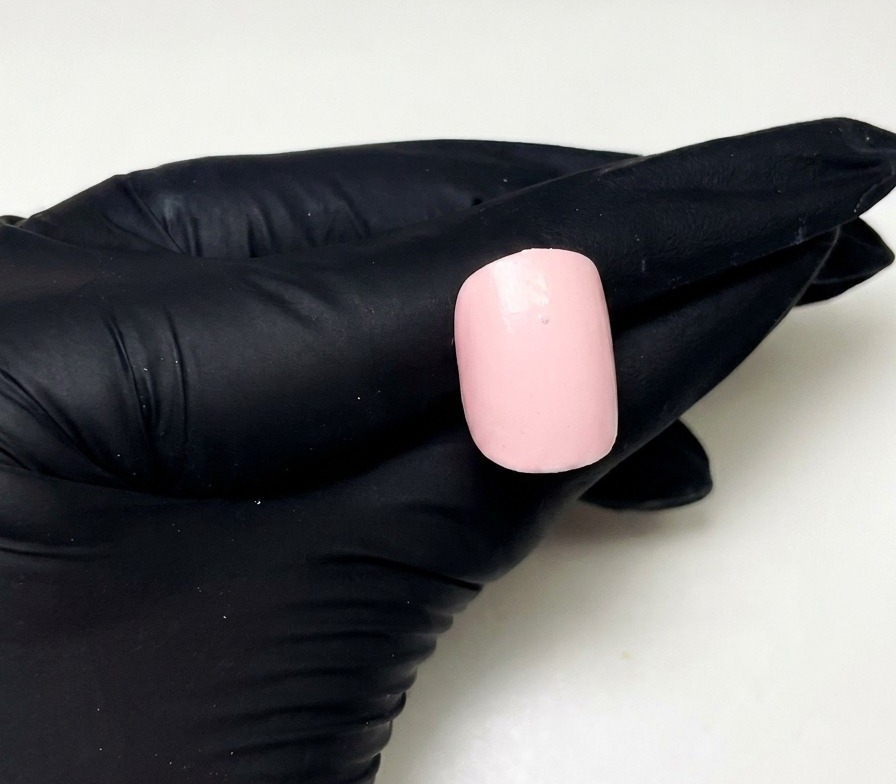 Primer plano de una uña rosa con un pequeño punto de builder gel rosa en el centro superior.