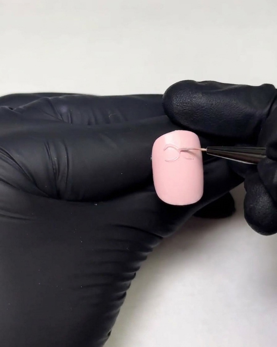 Manos con guantes dibujando el segundo bucle del lazo de gel 3D usando un pincel delineador fino.