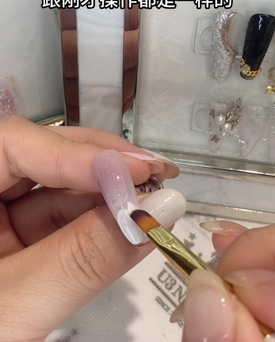 Un pincel difuminando gel blanco en la mitad inferior de una uña ombré.