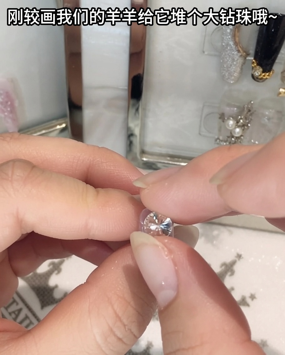 Un par de pinzas sosteniendo y posicionando un cristal de pedrería grande.