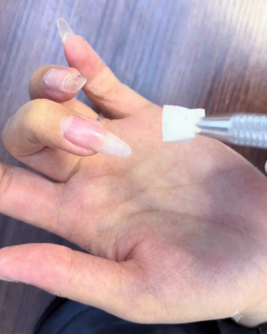 Aplicando gel blooming blanco y rosa sobre la superficie de una uña para formar un efecto ombré.