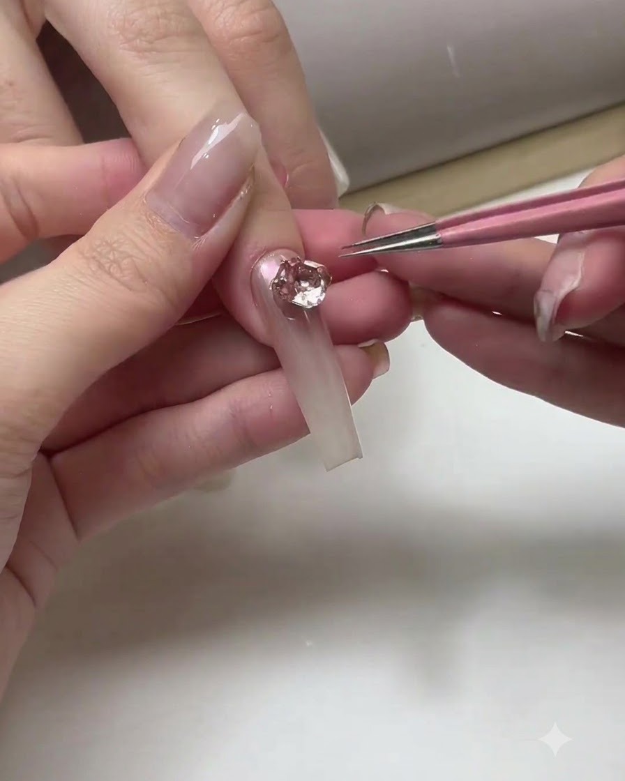 Manicurista aplicando una capa de top coat transparente sobre uñas ombré ya terminadas.