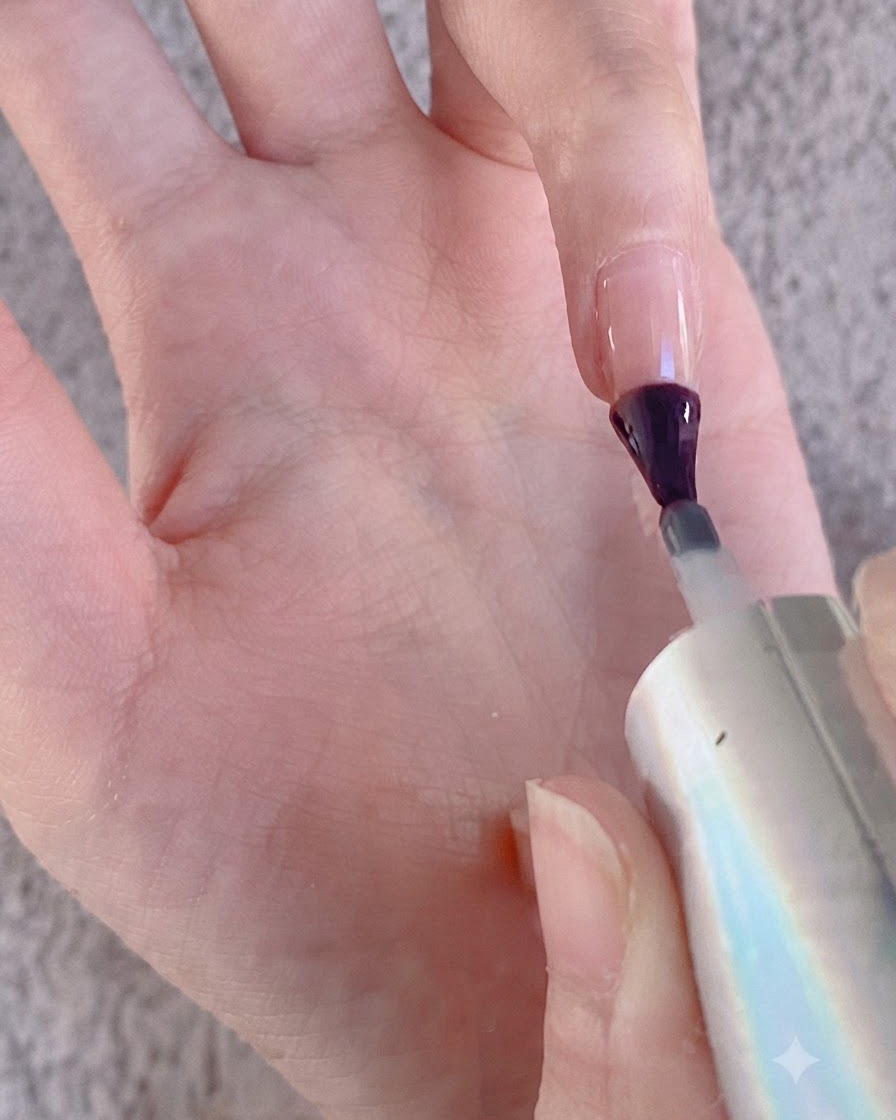Un pincel de uñas aplicando gel sobre la superficie de un dedo en preparación para el polvo cromado.