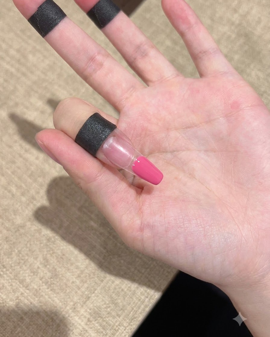 Un primer plano de un dedo con gel rosa aplicado ordenadamente en la zona de la punta.