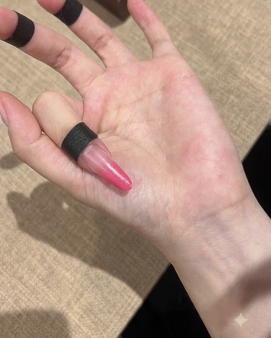 Una mano colocada bajo una lámpara UV compacta para curar las uñas con degradado rosa.