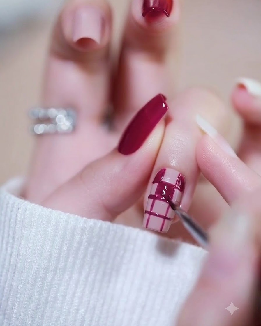 Una mano colocada bajo una lámpara de uñas para curar la segunda capa de esmalte en gel magenta.