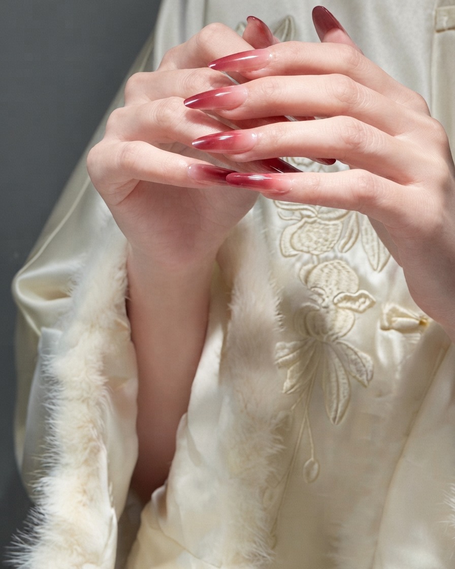 Dedos deslizándose delicadamente entre sí para demostrar la textura suave de las uñas de gel rojas terminadas.