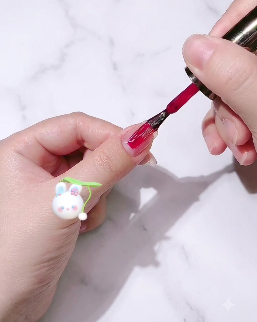 Un pincel de esmalte de uñas aplicando esmalte en gel rojo rosa sobre una uña.