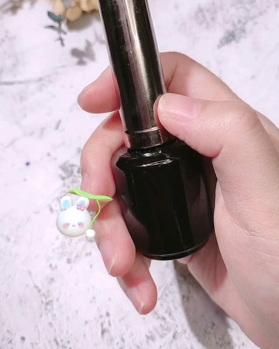 Un pincel de uñas aplicando una capa superior mate sobre una uña de color rojo rosa vibrante.