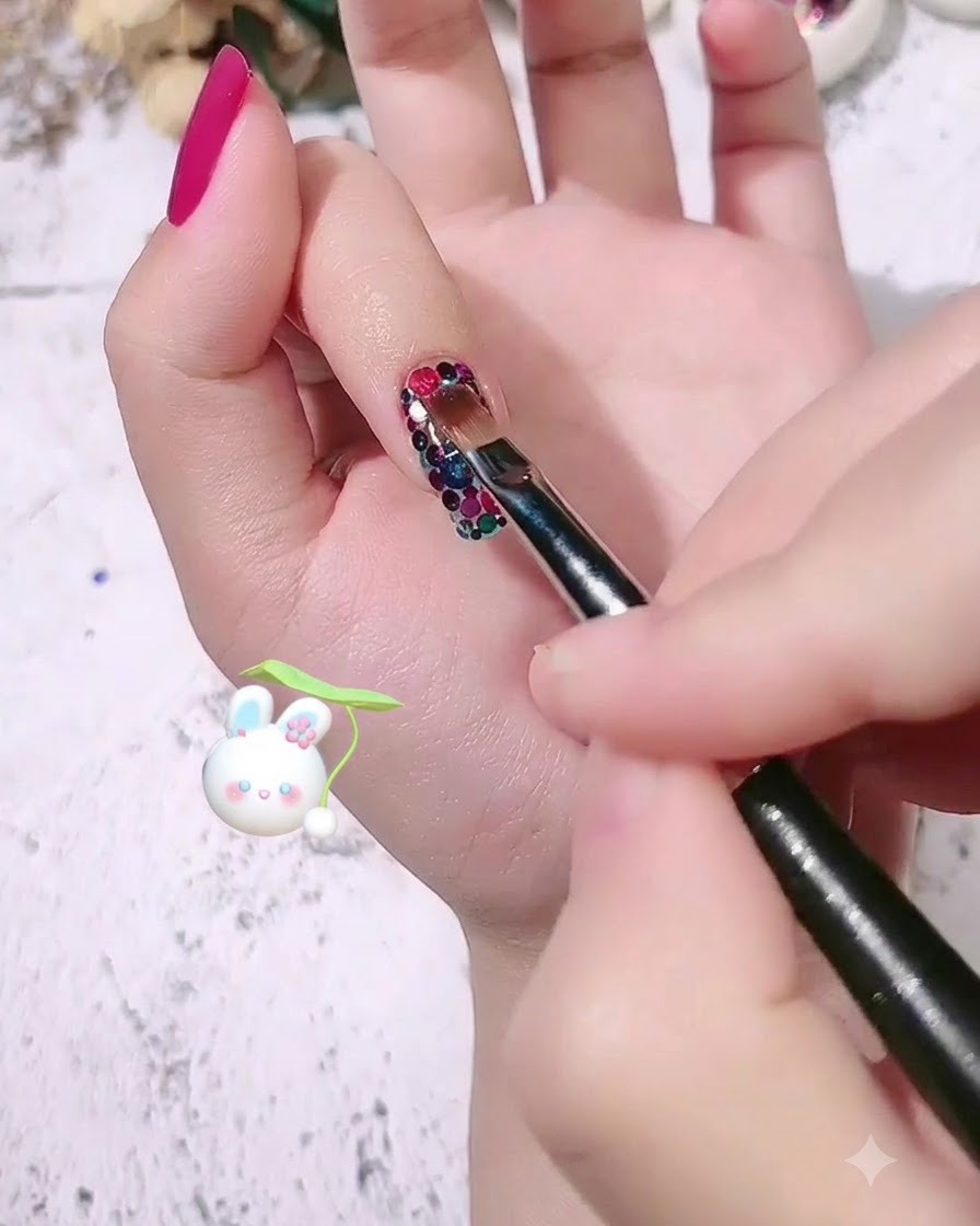 Un pincel de uñas aplicando una capa transparente de gel de modelado sobre el diseño de uñas con lentejuelas en patrón.