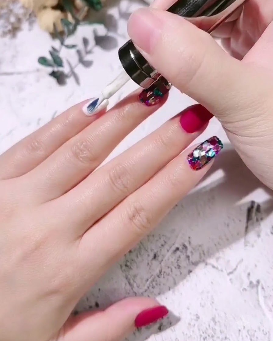 Un pincel de uñas aplicando esmalte en gel blanco lechoso sobre la uña de un dedo meñique.