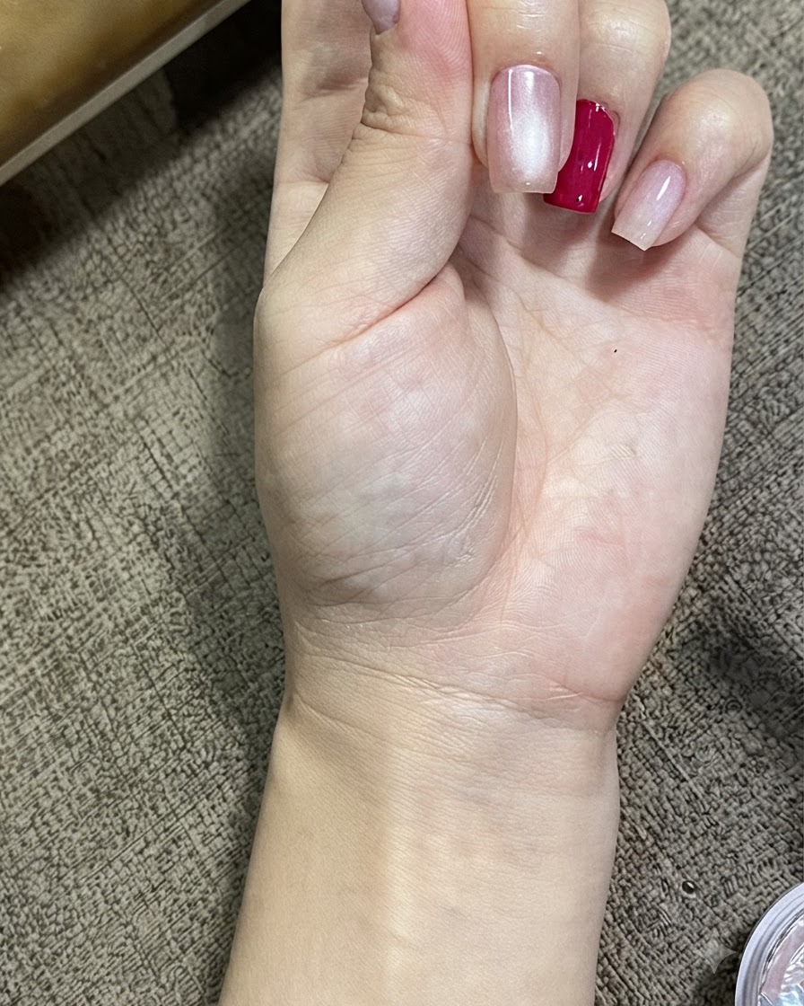 Una vista en primer plano de una mano que muestra uñas tratadas con gel cat eye magnético, mostrando un efecto de esfera brillante y luminosa.
