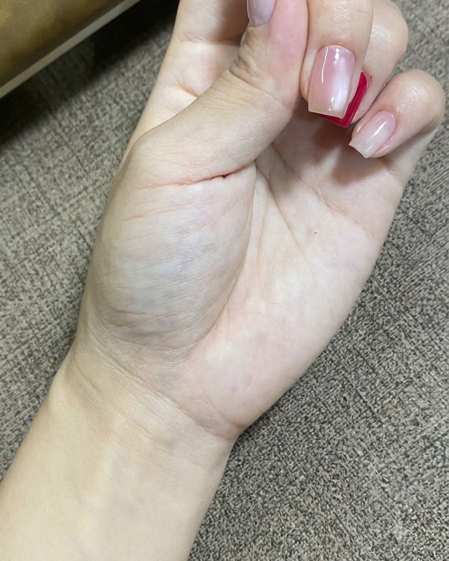 Una toma en primer plano de una mano descansando mientras una lámpara LED UV portátil cura el esmalte en gel de las uñas.