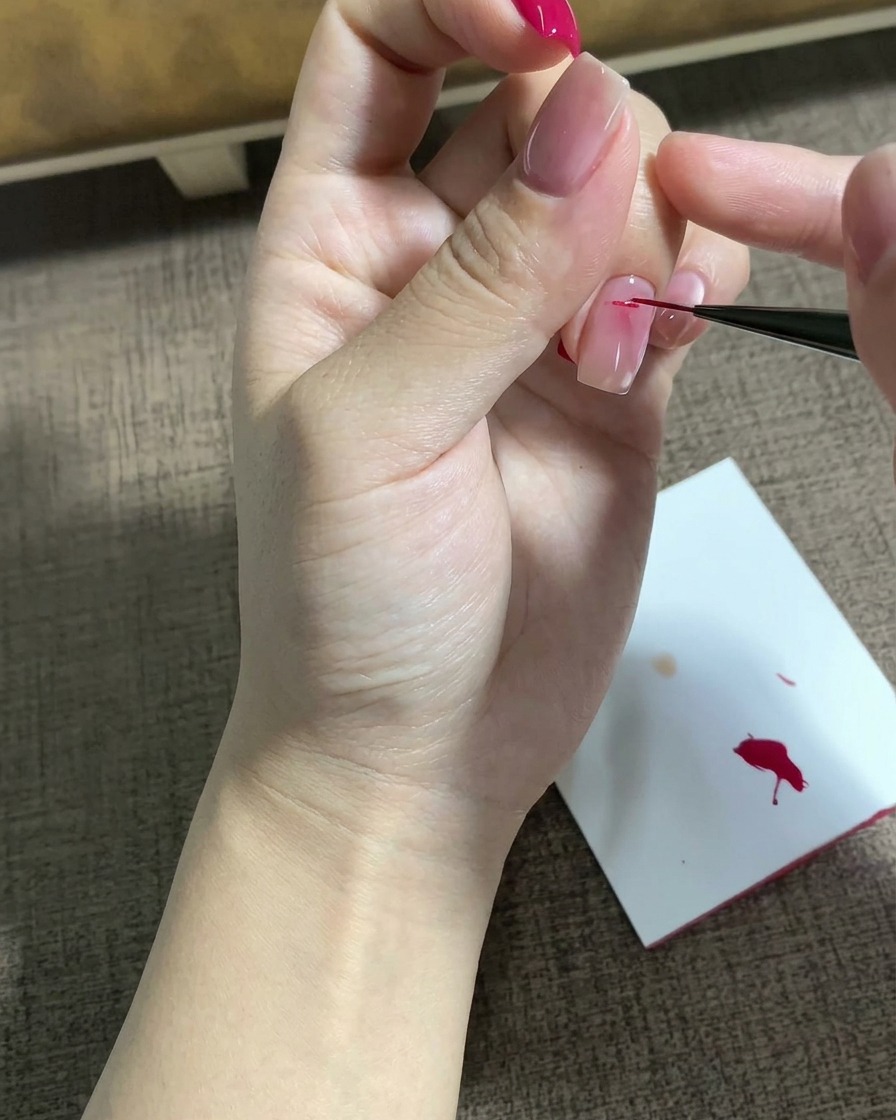 Un pincel delineador fino dibujando un motivo de estrella magenta detallado sobre una superficie de uña preparada.
