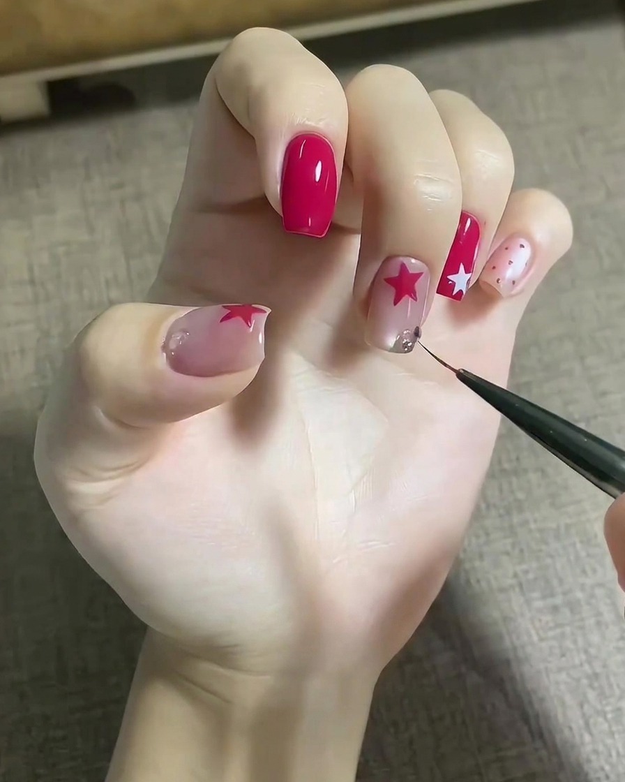 Una herramienta fina colocando gemas de cristal brillantes sobre una gota de gel adhesivo en una uña decorada.