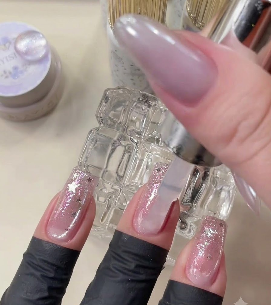 Un pincel de top coat aplicando gel transparente sobre el arte de uñas terminado.