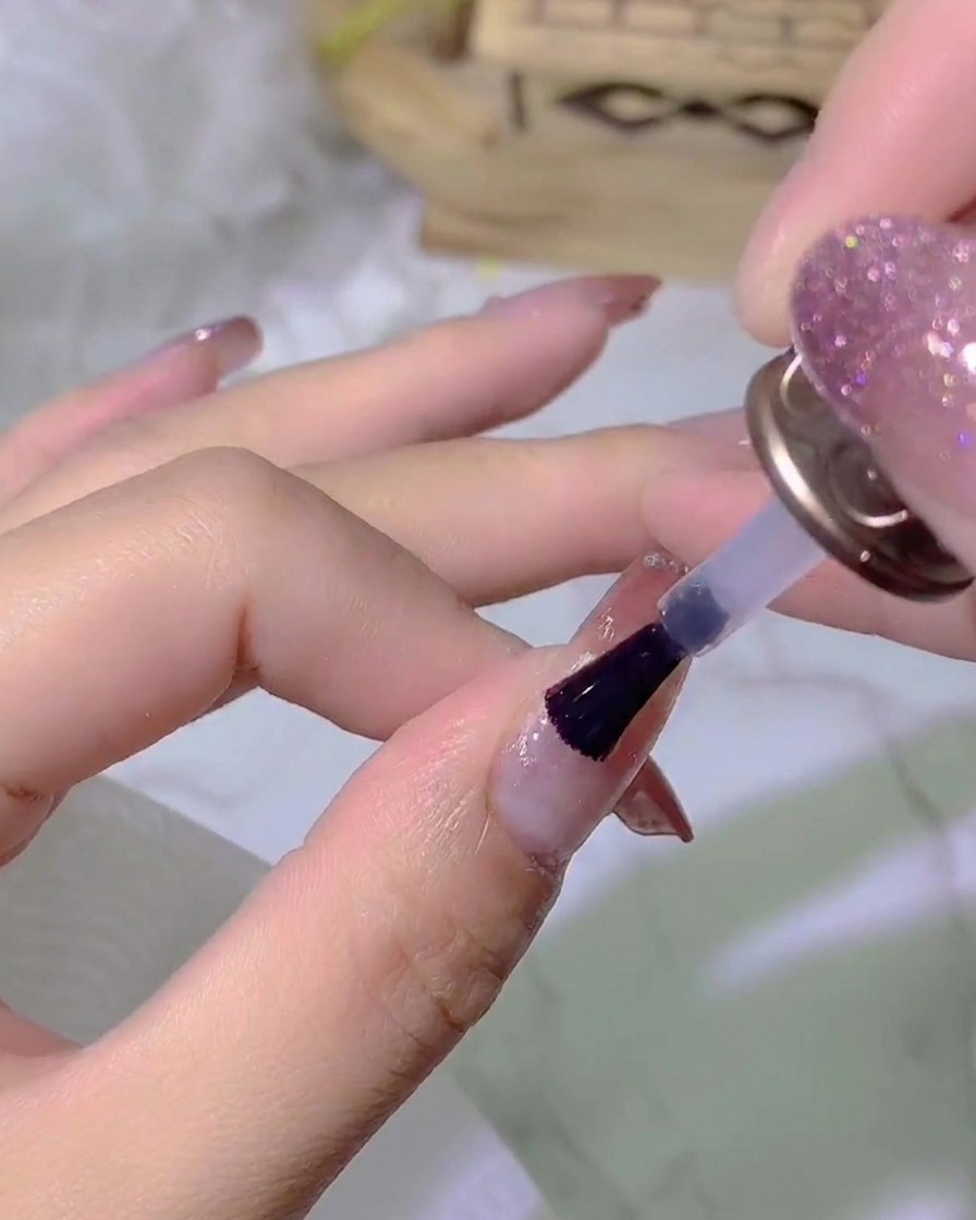 Una mano colocada bajo una lámpara de uñas UV/LED curando la capa de top coat.