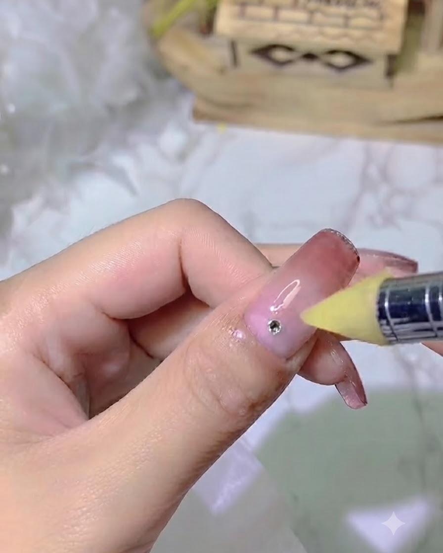 Una herramienta de uñas aplicando un punto preciso de pegamento adhesivo fuerte sobre una uña con degradado.
