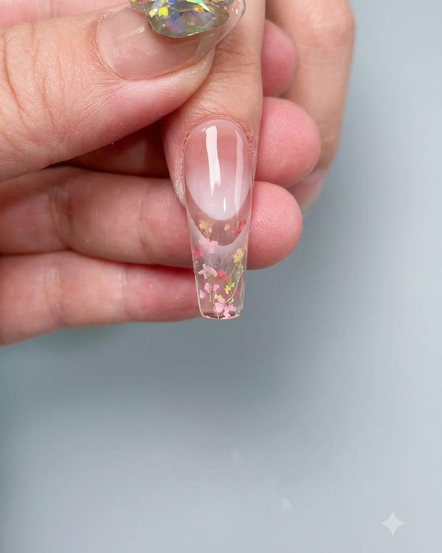 Una uña con flores secas incrustadas curándose dentro de una lámpara UV/LED profesional.