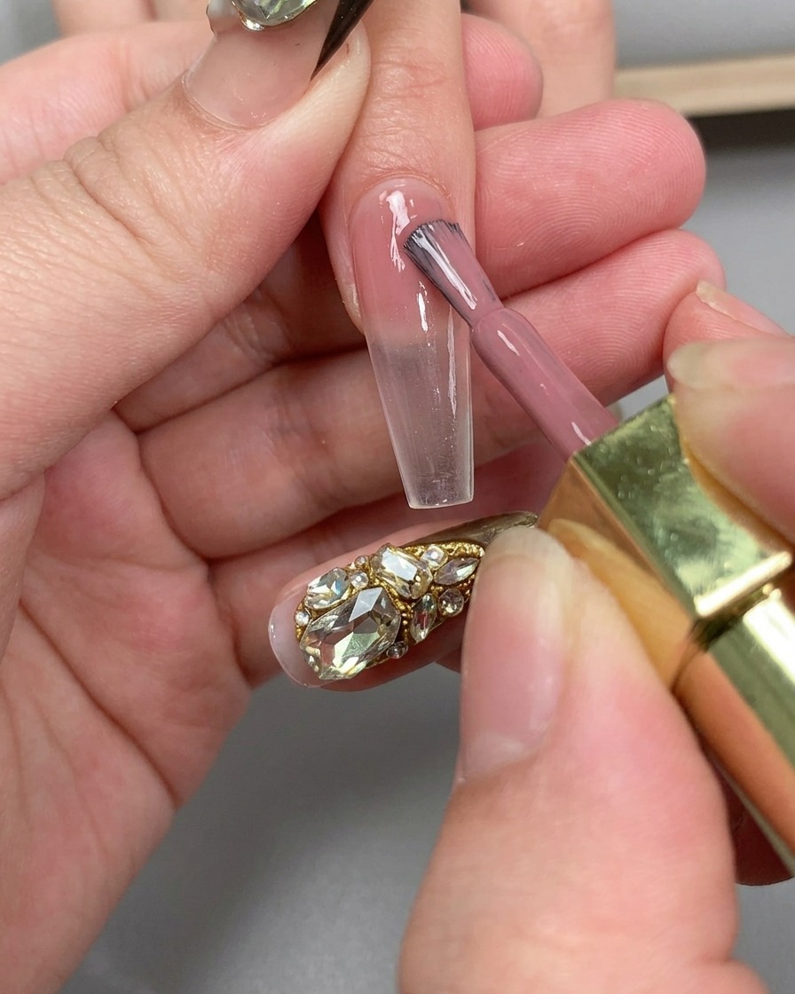 Una mano posicionada bajo una lámpara UV para uñas para curar la aplicación de la capa base.