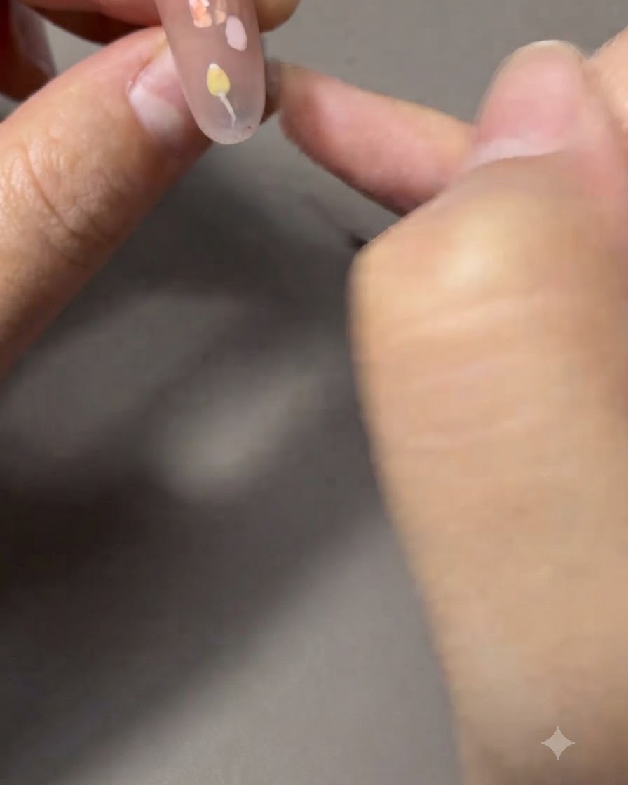 Un pincel delineador fino pintando tallos y hojas verdes delgadas conectados a un tulipán.