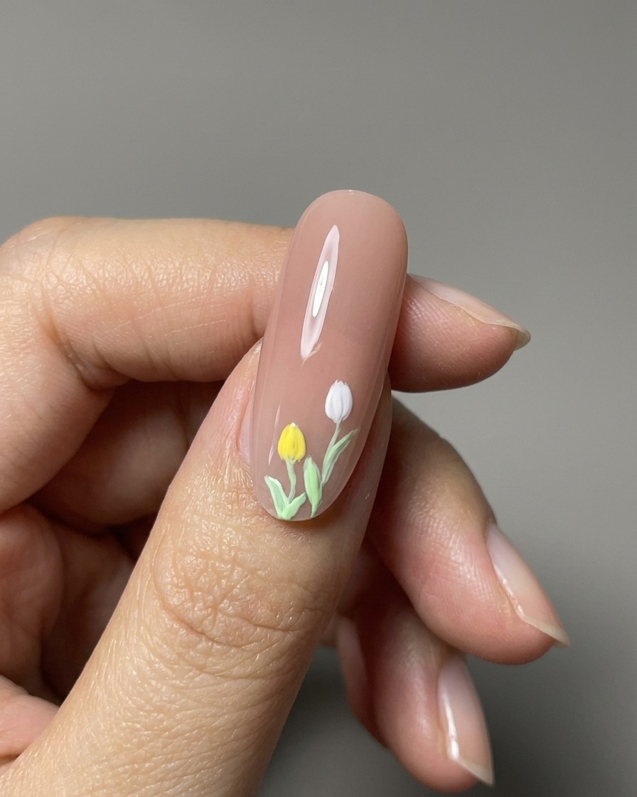 Vista de cerca de tulipanes pintados en 3D terminados sobre una uña nude brillante.