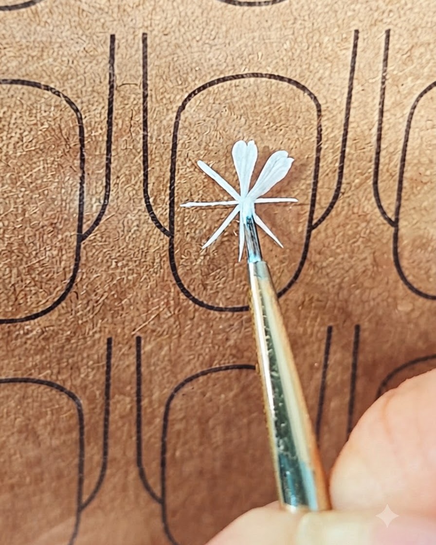 Un pincel fino de nail art colocando gel blanco para formar un segundo pétalo en un tablero de práctica.