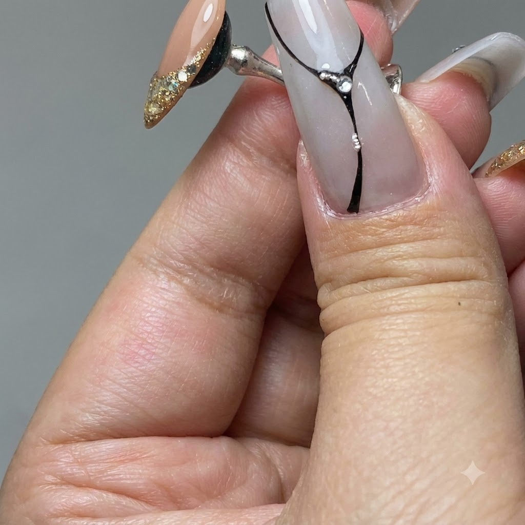 Un pincel de uñas esparciendo gel de platino dorado sobre la punta de una uña de práctica.