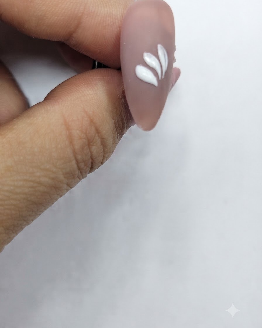 Una uña con múltiples trazos de pétalos blancos dispuestos en un patrón circular parcial.