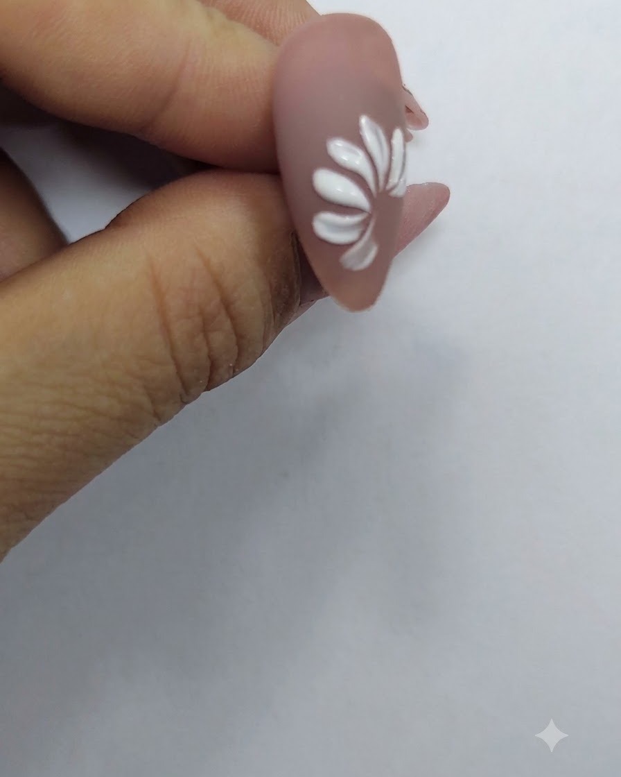 Un anillo completo de pétalos blancos que forman la figura completa de una flor de margarita sobre un fondo de uña nude.