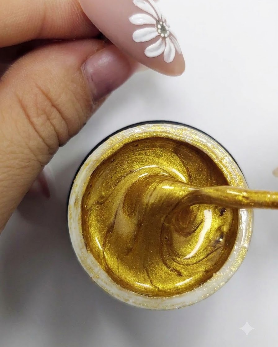 Un pincel delineador fino recogiendo y cargando esmalte en gel dorado vibrante desde el interior de un recipiente abierto.