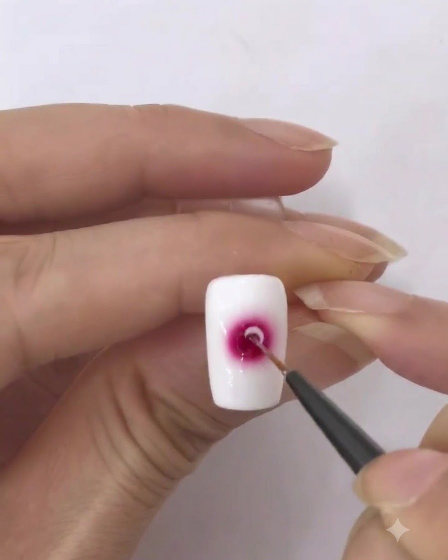 Un pincel delineador fino cargado con una pequeña cantidad de esmalte en gel blanco.