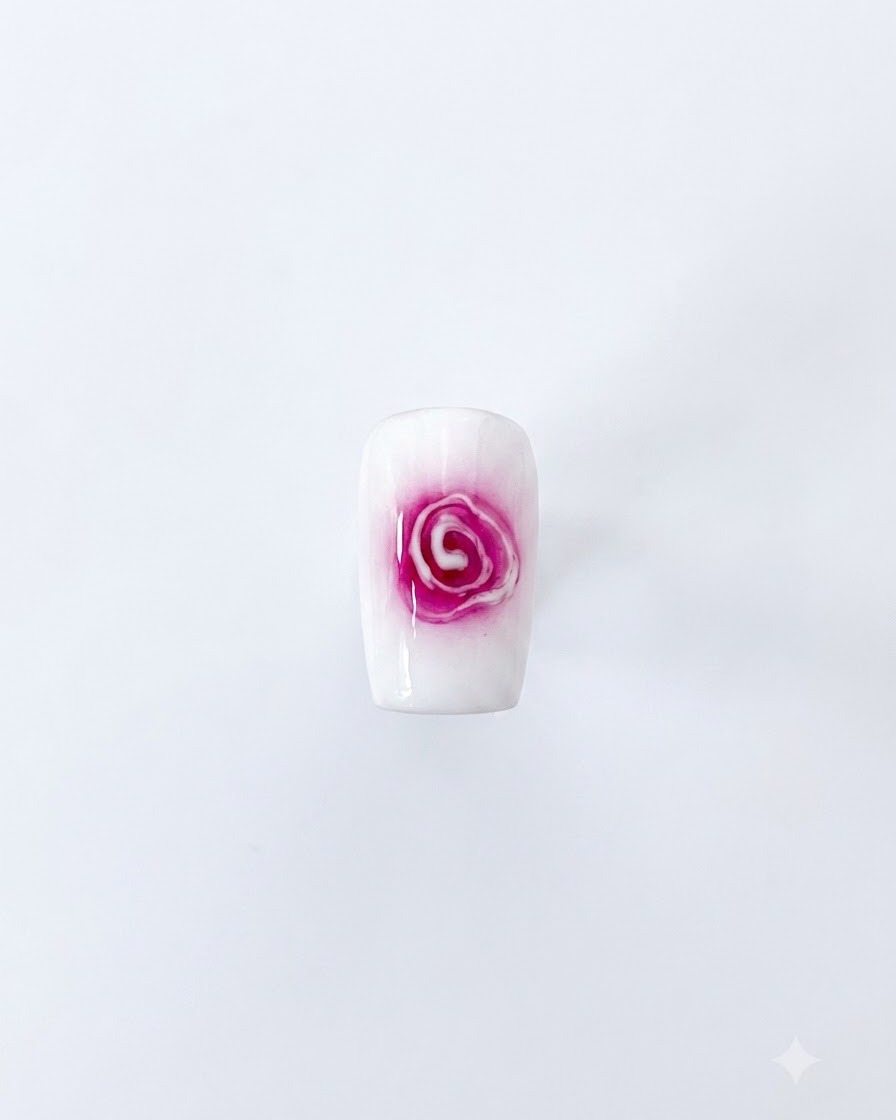 Un diseño completo de arte de uñas de rosa difuminada con un centro rojo y pétalos blancos suaves que se expanden sobre un fondo blanco.