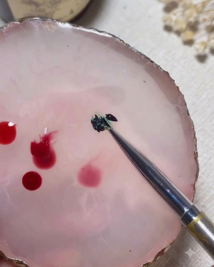 Una herramienta de mezcla combina colores de gel verde y negro sobre una paleta de mármol rosa.