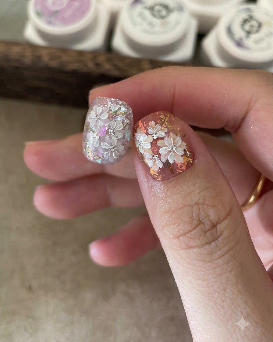 Una esponja aplicadora frotando polvo efecto espejo dorado sobre los detalles de hojas pintadas en una uña.