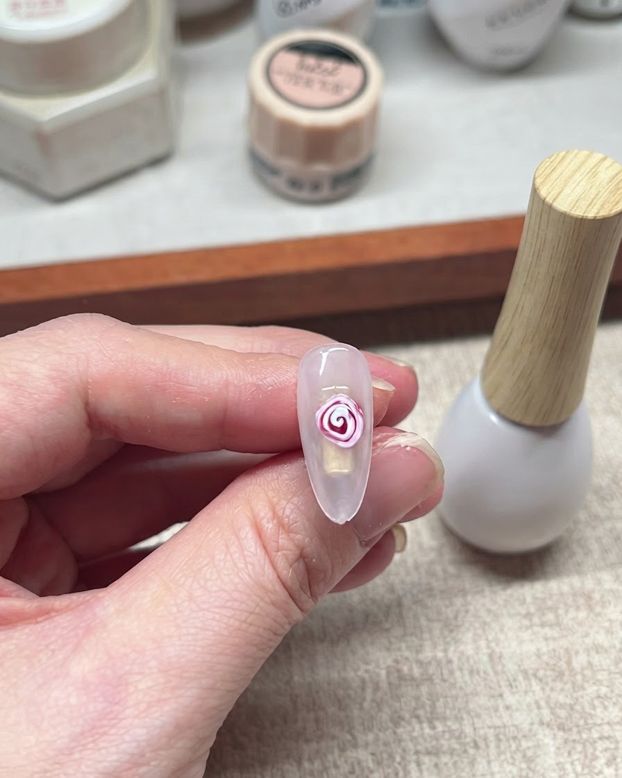 Un diseño terminado de rosa con blooming gel en tonos rojo y blanco sobre una uña.