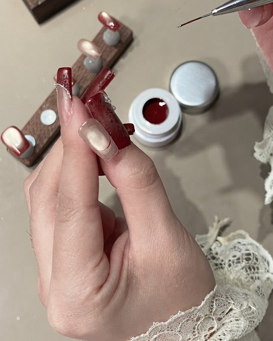 Un pincel delineador rellenando el área de la punta francesa con gel rojo terciopelo opaco.