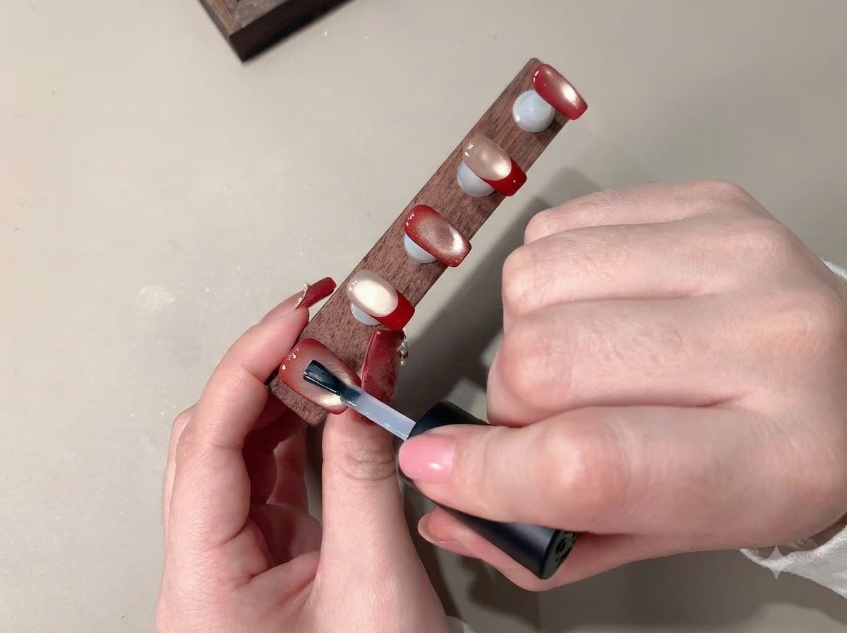Un pincel aplicando una capa superior transparente para sellar el arte de uñas terminado.