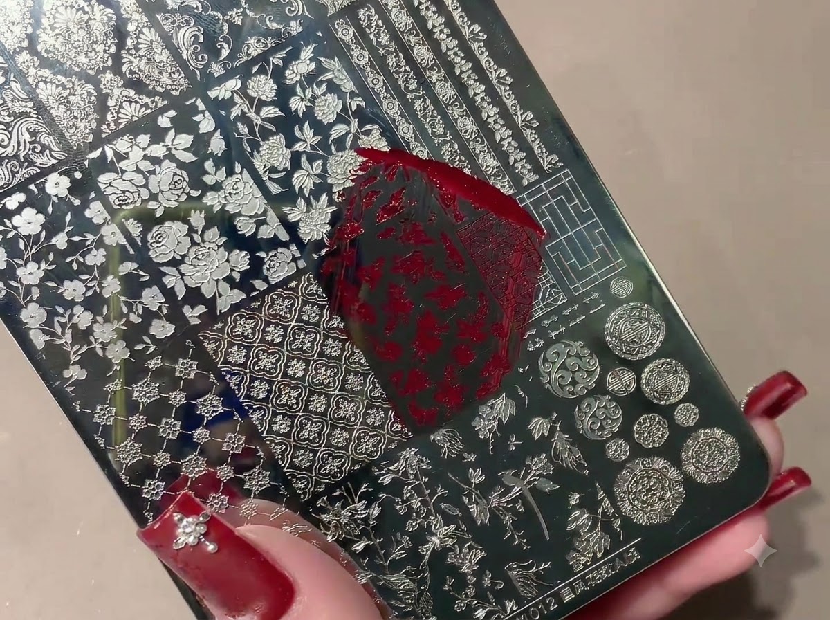Un sello de silicona recogiendo un patrón rojo estampado desde una placa metálica de estampados.