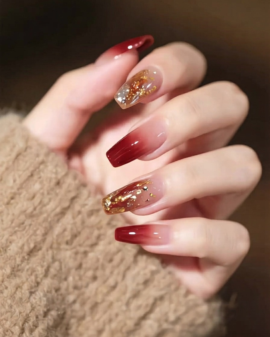 Una toma de cerca de una mano con arte de uñas detallado, que muestra un cristal llamativo y finas líneas doradas.