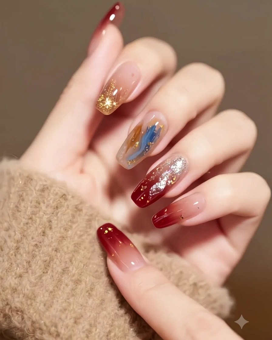Vista detallada de uñas degradadas en burdeos con estrellas incrustadas y escamas doradas sobre un fondo de textura beige.