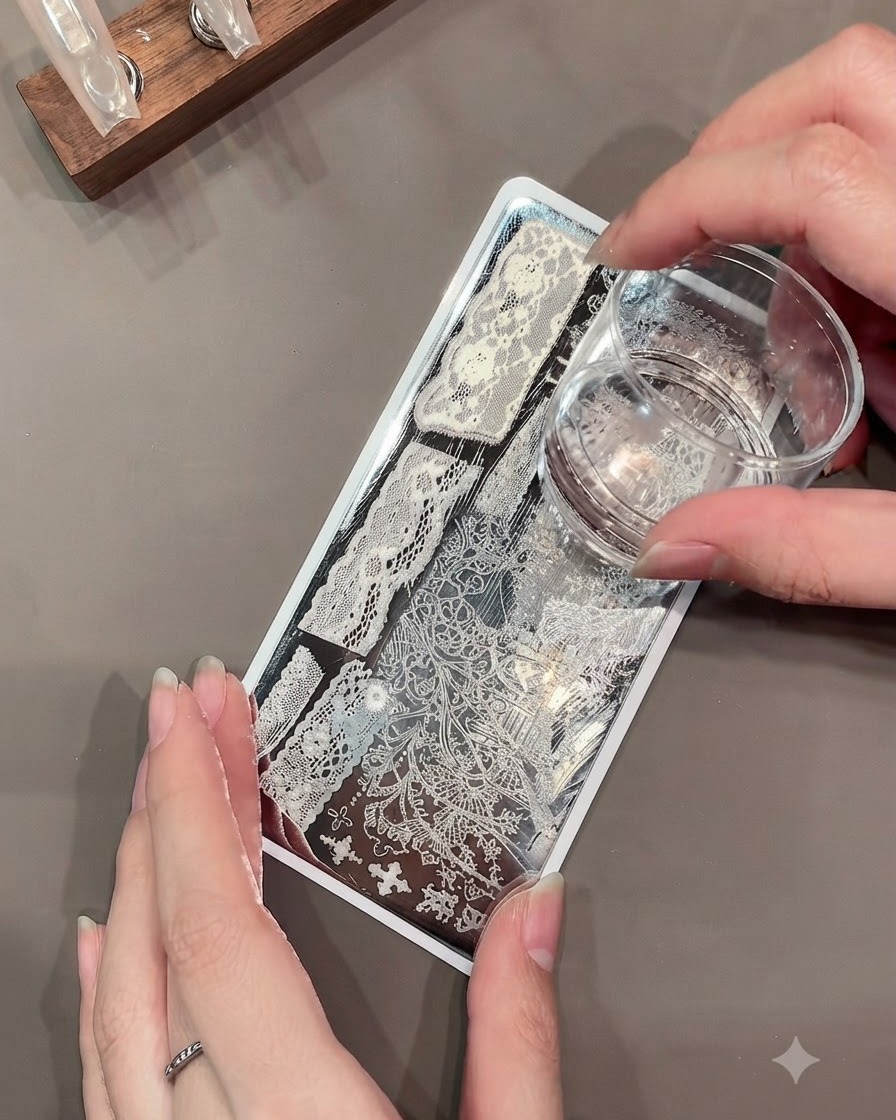 Un sello de gel transparente recogiendo un intrincado patrón de encaje blanco de una placa de estampado metálica.