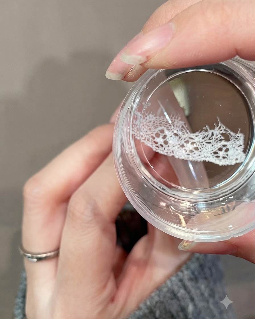 Un sello de gel transparente transfiriendo un delicado diseño de encaje blanco en la porción superior de una uña.