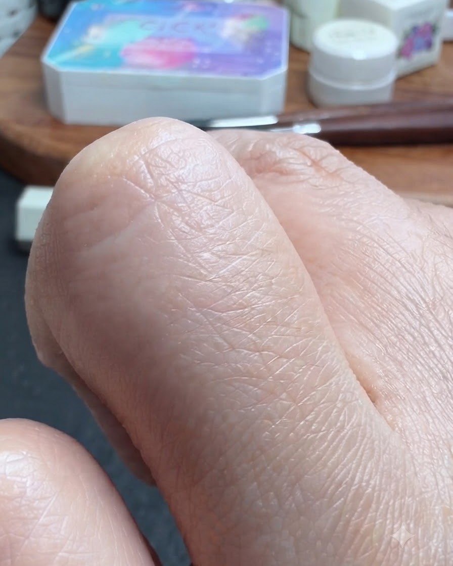 Una vista de cerca de un pulgar siendo humedecido ligeramente con alcohol.
