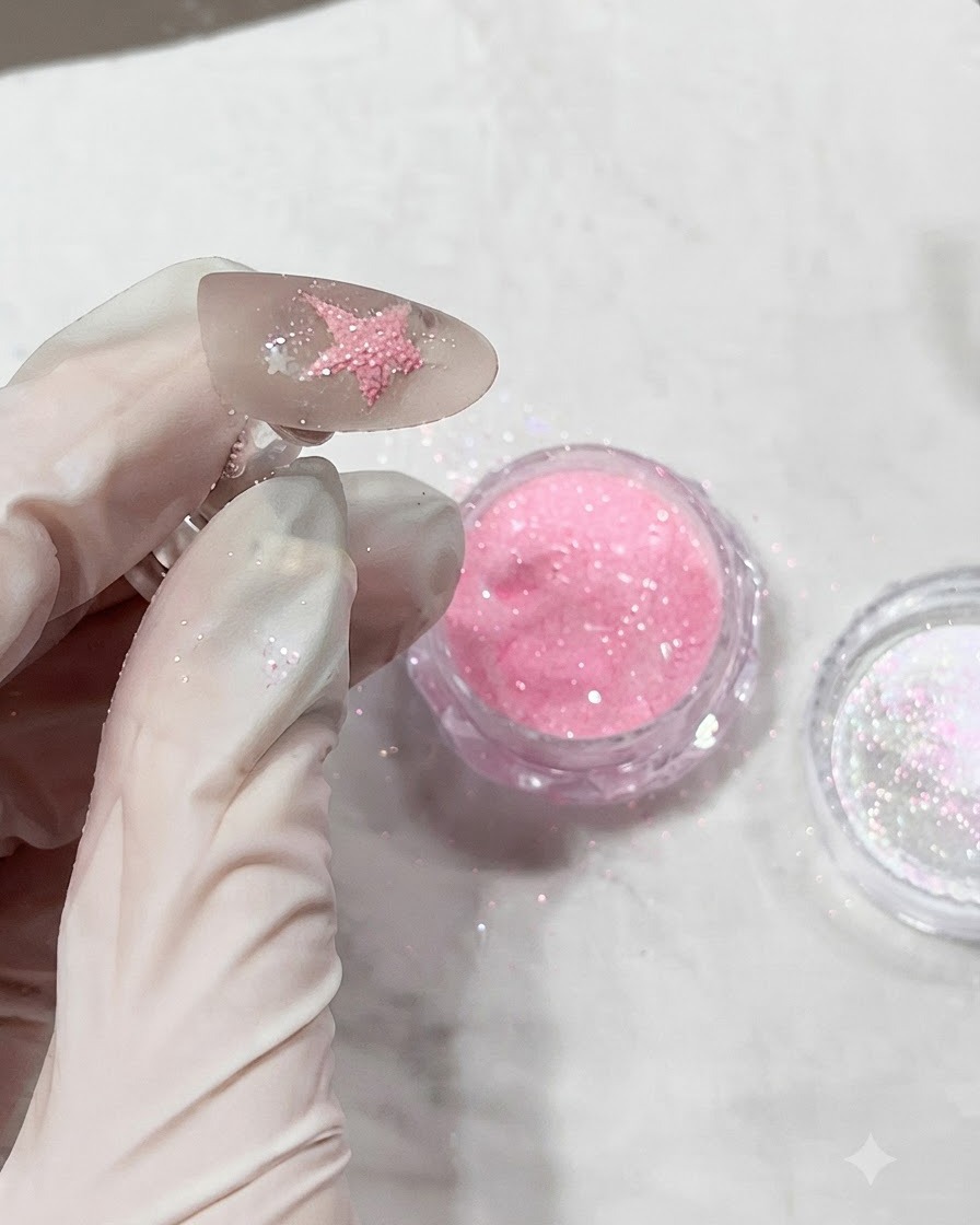 Una uña cubierta con polvo de diamante rosa texturizado justo antes de ser curada bajo una lámpara.