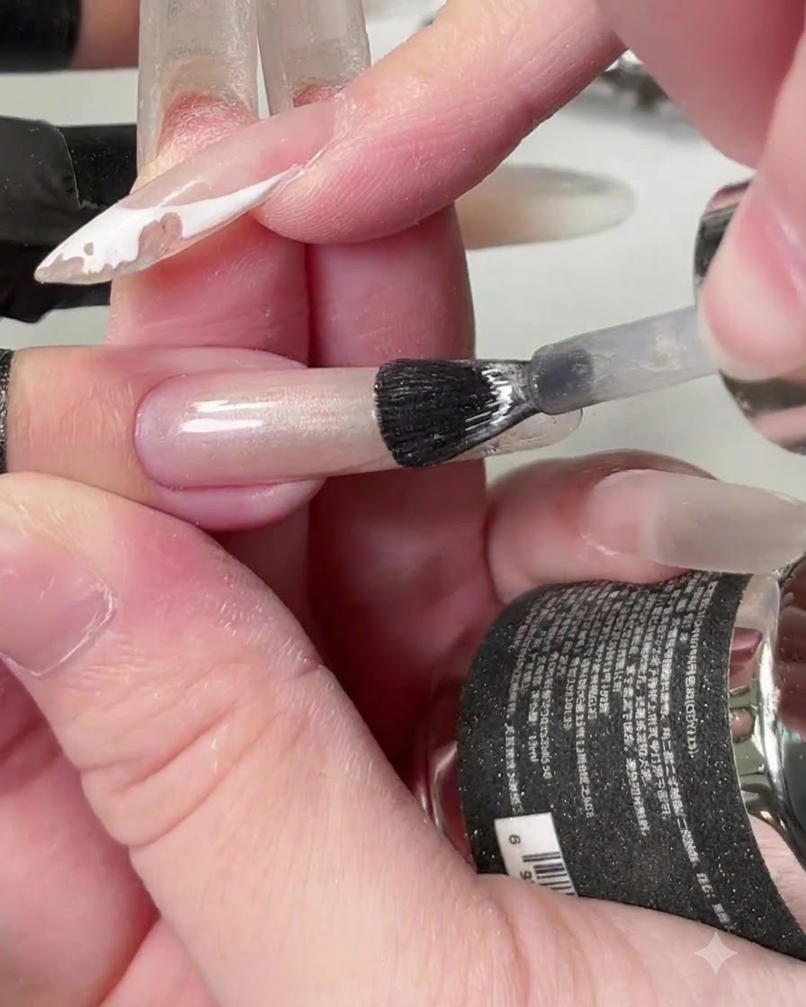 Una brocha aplicando gel de ojo de gato cristalino transparente a lo largo de toda la uña.