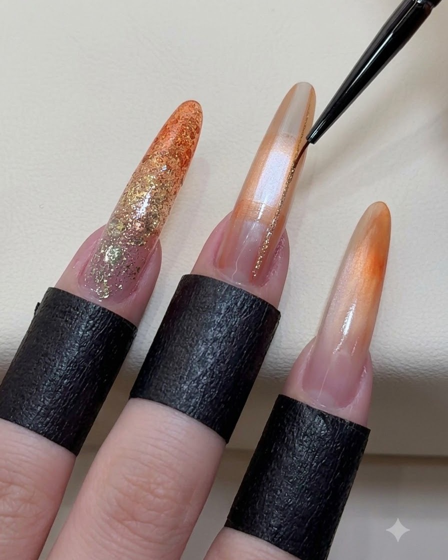 Un pincel delineador fino aplicando líneas brillantes de oro champán sobre una uña de gel decorada.